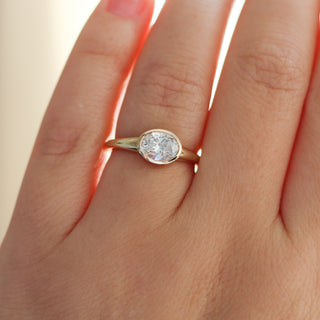 Yellow gold ring with a bezel set white oval cut diamond, on hand