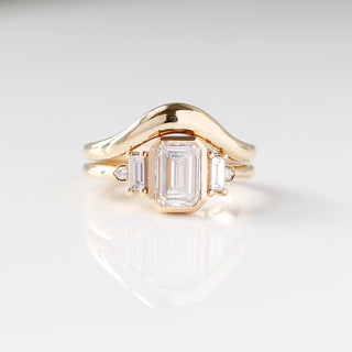 Yellow gold ring with a bezel set white emerald cut diamond and four white diamond accents with a yellow gold wedding band, front view