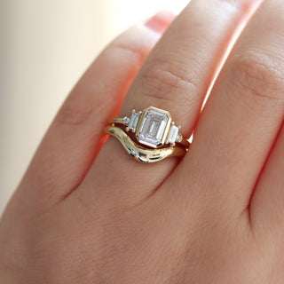 Yellow gold ring with a bezel set white emerald cut diamond and four white diamond accents with a yellow gold wedding band, on hand