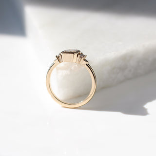 Yellow gold ring with a bezel set white emerald cut diamond and four white diamond accents, side view