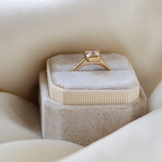 Yellow gold solitaire engagement ring with a bezel set peach radiant cut sapphire, in ring box, side view