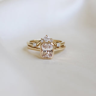 Yellow gold solitaire engagement ring with a bezel set peach radiant cut sapphire stacked with a white diamond curved wedding band, front view