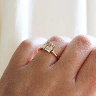 Yellow gold solitaire engagement ring with a bezel set peach radiant cut sapphire, on hand, quarter view