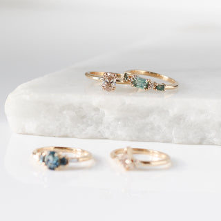 Various yellow gold rings with gemstones on a white marble surface, handmade in toronto
