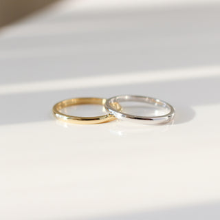 One yellow gold and one white gold 2mm band on white background