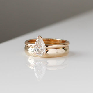 Classic light 4mm band in yellow gold stacked with a pear white diamond ring, quarter view