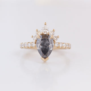 Yellow gold engagement ring with a pear fancy grey diamond framed by round white diamonds in a crown style, with a diamond pavee on the band