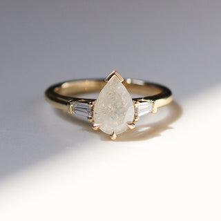 Yellow gold engagement ring with an icy pear diamond and two baguette diamond accents