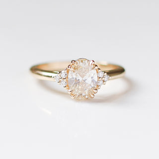 Yellow gold engagement ring with an oval champagne diamond and clusters of round white diamonds