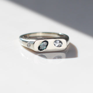 Platinum engagement signet style ring with a teal sapphire and a white diamond flush set into the signet