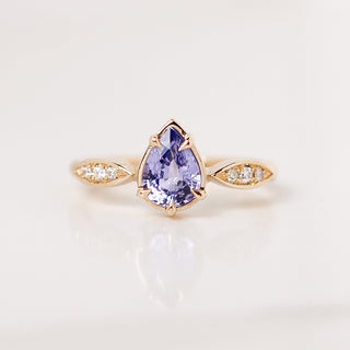 Yellow gold engagement ring with a purple pear sapphire and round white diamond accents