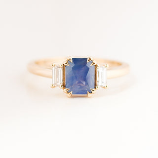 Yellow gold engagement ring with a radiant cut periwrinkle blue sapphire and baguette diamond accents