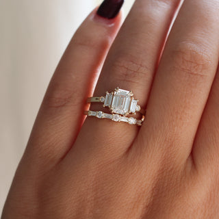 Yellow gold wedding band with baguette cut and round brilliant cut lab diamonds stacked with an emerald cut white diamond engagement ring, on hand