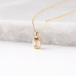 Gold necklace with a pendant on a marble surface