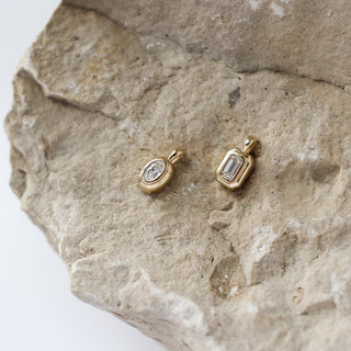 gold diamond pendants on a stone surface 