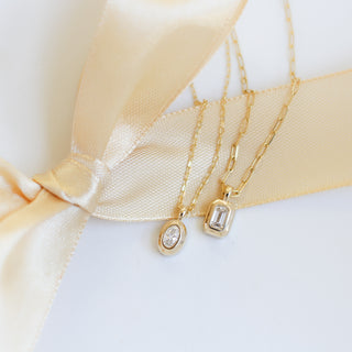 Two gold necklaces with diamond pendants on a white background