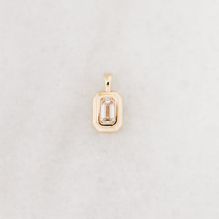 Gold pendant with a rectangular stone on a light gray background