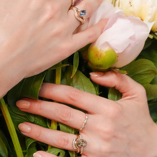 Multiple engagement rings and wedding bands on hands, floral background