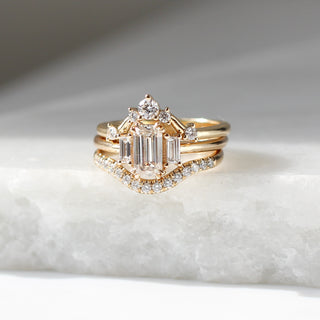 Diamond pave curved wedding band in yellow gold stacked with multiple rings, front view