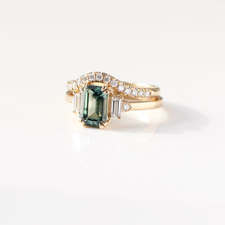 Diamond pave curved wedding band in yellow gold stacked with emerald cut green sapphire engagement ring, front view