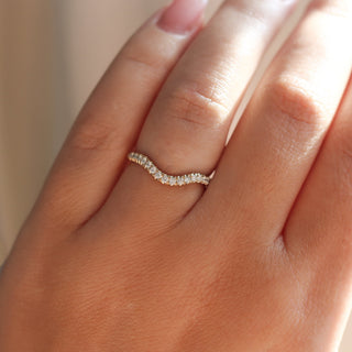 Diamond pave curved wedding band in yellow gold, on hand