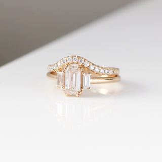 Diamond pave curved wedding band in yellow gold stacked with emerald cut diamond engagement ring, front view