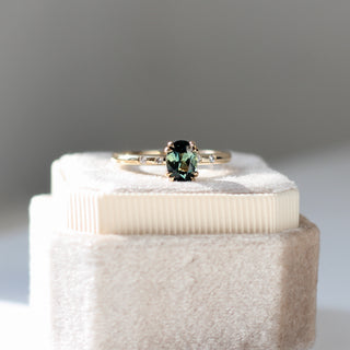 Yellow gold ring with green sapphire, placed on top of ring box