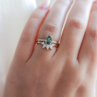 Yellow gold crown contour band with clear diamonds and a yellow gold ring with a green sapphire, on hand