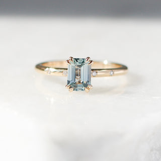 Yellow gold ring with a light blue emerald cut sapphire, front view