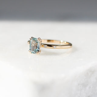 Yellow gold ring with a light blue emerald cut sapphire, quarter view