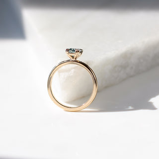 Yellow gold ring with a light blue emerald cut sapphire, side view