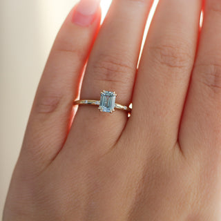 Yellow gold ring with a light blue emerald cut sapphire, on hand