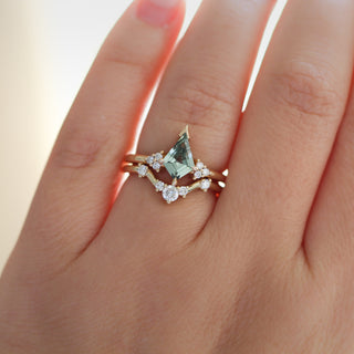 Yellow gold ring with a light green kite cut sapphire and a yellow gold curved wedding band with round white diamonds, on hand