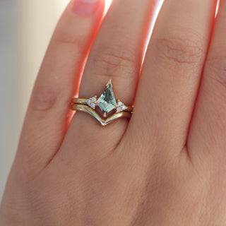 Yellow gold ring with a light green kite cut sapphire and a yellow gold pointed wedding band, on hand
