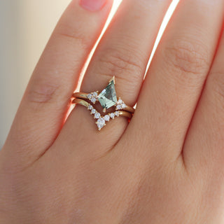Yellow gold ring with a light green kite cut sapphire and a yellow gold pointed wedding band with assorted white diamonds, on hand