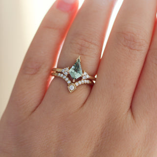 Yellow gold ring with a light green kite cut sapphire and a yellow gold pointed wedding band with round white diamonds, on hand