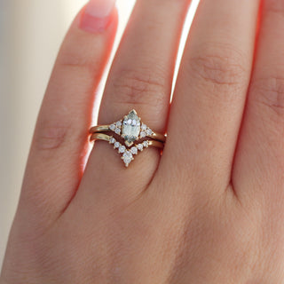 Yellow gold ring with a light green marquise cut sapphire with a yellow gold pointed wedding band with white diamonds, on hand