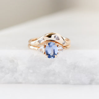 Yellow gold contour band with clear diamonds and a yellow gold ring with a blue sapphire, front view