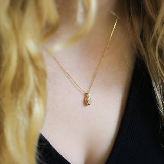 Gold necklace with a pendant worn by a person with blonde hair.
