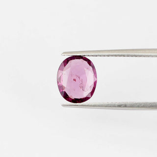 Oval shaped pink spinel in tongs