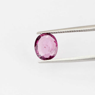 Oval shaped pink spinel in tongs