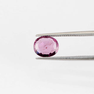 Oval shaped pink spinel in tongs