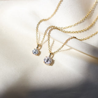 Two Round Lab Diamond Necklaces in yellow gold on white fabric
