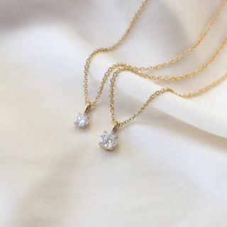 Two Round Lab Diamond Necklaces in yellow gold on white fabric