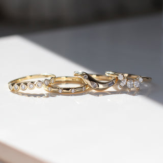 Set of gold rings with white and clear gemstones on a light background