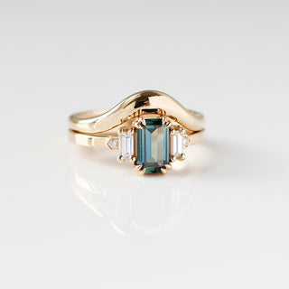 Yellow gold ring with a teal emerald cut sapphire and four white diamond accents and a yellow gold curved wedding band, front view