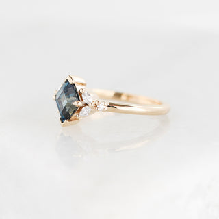 Yellow gold ring with a teal lozenge cut sapphire and white diamond accents, quarter view