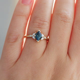 Yellow gold ring with a teal lozenge cut sapphire and white diamond accents, on hand