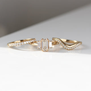 Twilight diamond wave band beside an emerald cut white diamond engagement ring and a straight white diamond pave band, front view