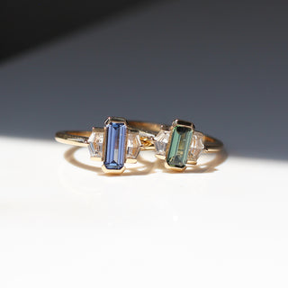 Two yellow gold engagement rings with half bezel set coloured sapphires and white sapphire shield accents side by side, front view